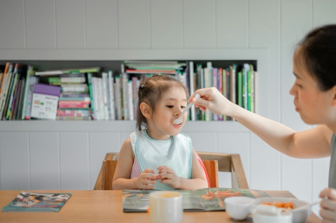 child being fed with a spoon at table