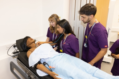 Medical Degree students using a stethoscope on a manikin