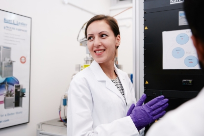 A female student in a lab coat with purple gloves