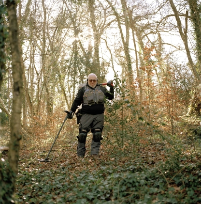a photo of a man with a metal detector in the woods