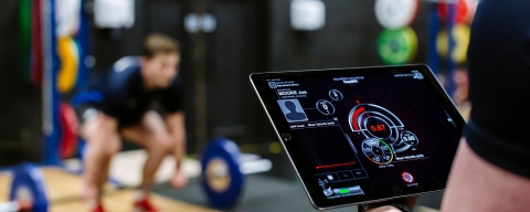 A student tracking an athlete's progress in the gym