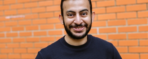 Headshot of male student stood in front of orange brick wall