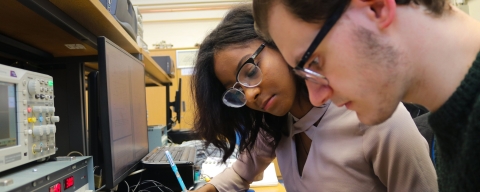 Two students working on an electronic engineering project added