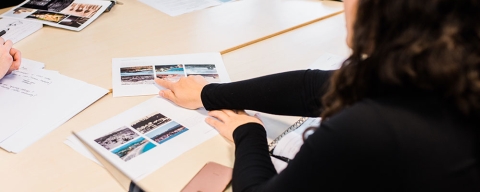 Students working at a table covered in pictures of building locations