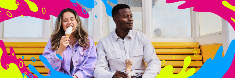 Two students seated on a bench, happily eating ice cream together.