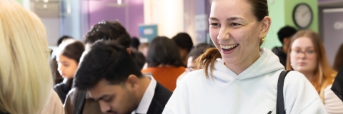 A female student is speaking to a member of staff in the Careers and Employability Centre while writing notes.