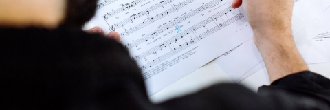 Person marking sheet music with light blue pencil