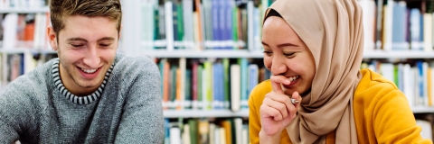 Students in the library studying, smiling and laughing