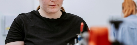 Student uses automatic Jigsaw on workstation to cut out component for model inside Technology Facilities