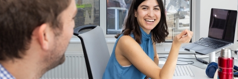 Woman in office environment smiling with colleague