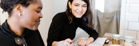 2 female students laughing while discussing notes
