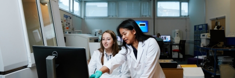 Researchers in lab coats with computer and equipment