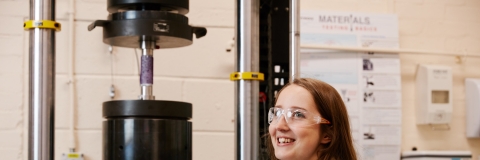 A female student standing in front of hydraulic equipment in our Rock Mechanics Laboratory