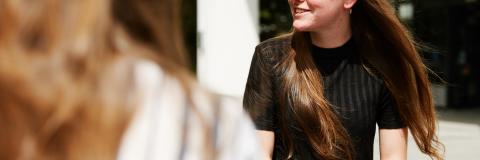 Students sat on grass and talking in the sun