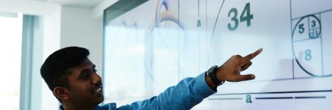 Male student pointing towards graph on screen