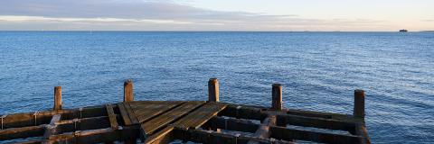 Large expanse of sea with wood planks in foreground