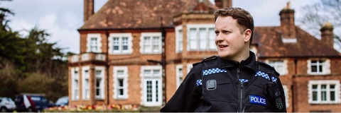 Police officer in uniform in front of criminology building