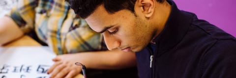a male student from Iraq drawing in class