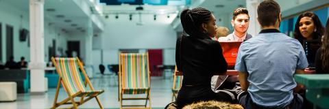 A group of students standing around a podium in the Third Space area of the Student's Union.