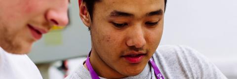 A male student from Myanmar demonstrating an item to another student