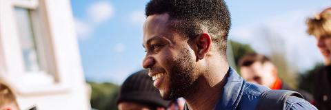 smiling male student from nigeria walks with friends by southsea common