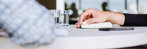 Close up of arm resting on table with notebook and pen