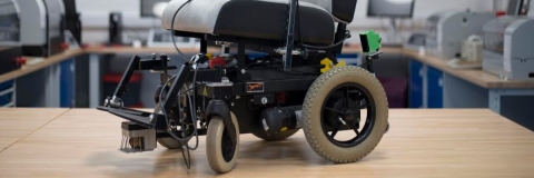 A powered wheelchair fitted with sensors on a work bench in an engineering lab