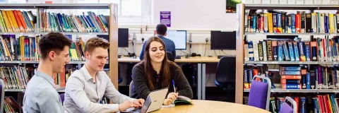 Three students studying in the library