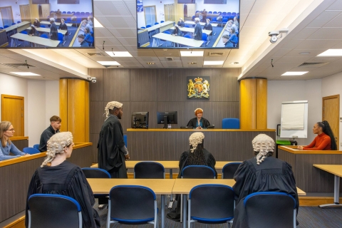 A group of students in a replica court room, simulating a trial.