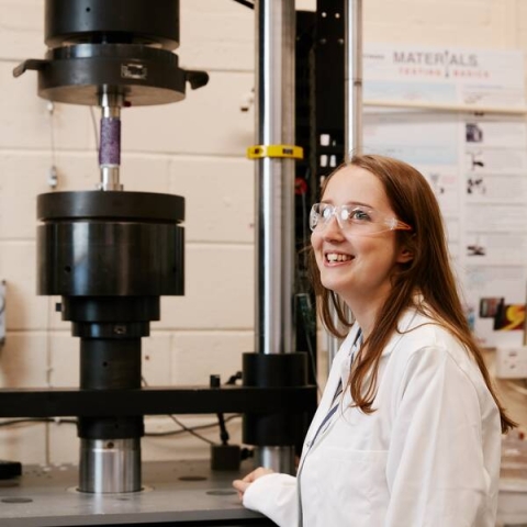A female student standing in front of hydraulic equipment in our Rock Mechanics Laboratory