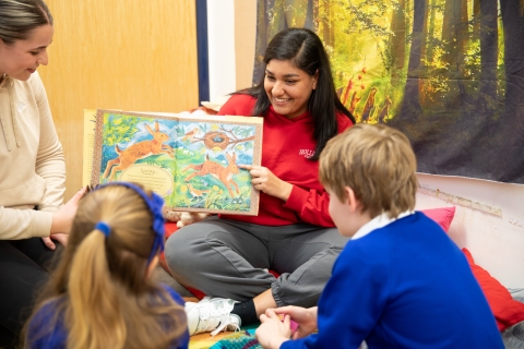 Woman reading a book to two school children