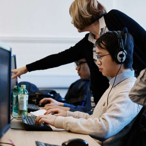 Teacher helping students at computer