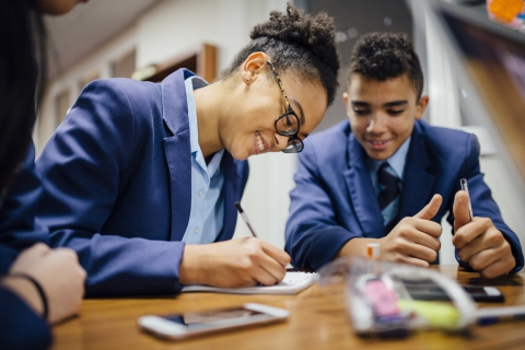 Two students smiling as they work together at a desk