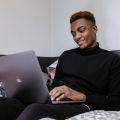 Male student sitting on a bed in halls