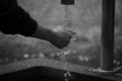 black and white image of water coming out of outside tap