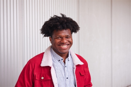 A student wearing a red jacket and smiling