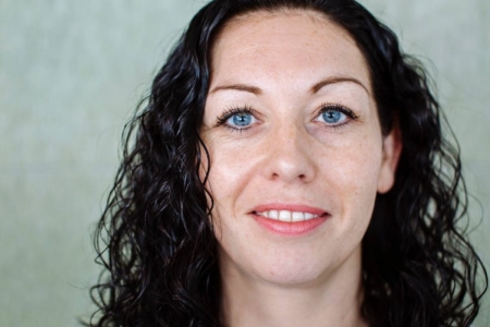 A woman with curly hair, smiling