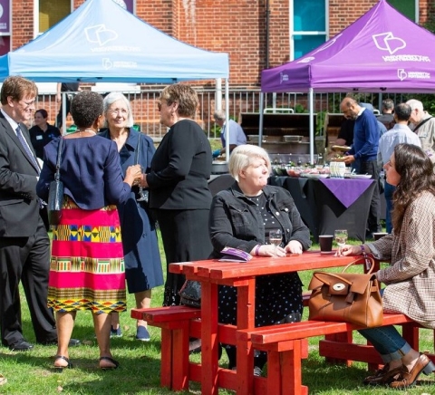 Alumni sitting outside on benches and under marques