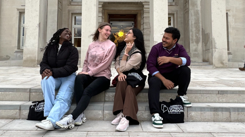 4 students sat on steps outside laughing together